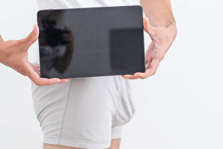a man in underwear is holding a tabletの写真素材