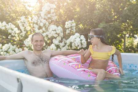 The father with little daughter have fun in the pool. Dad plays with the child. The family enjoy summer vacation in a swimming pool jumping, spinning, splash water.の写真素材