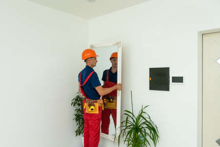 Furniture assembling. the repairman installs the mirror at living room of new house.の写真素材
