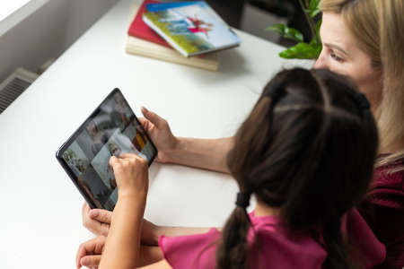 mother and daughter using digital tablet for online chatting from homeの写真素材