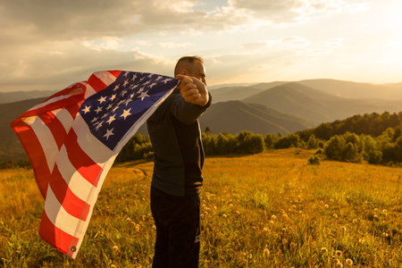 Young man proudly waving the American flag at sunset