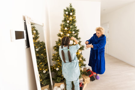 winter holidays and family concept - happy grandmother and baby granddaughter near christmas tree at homeの写真素材