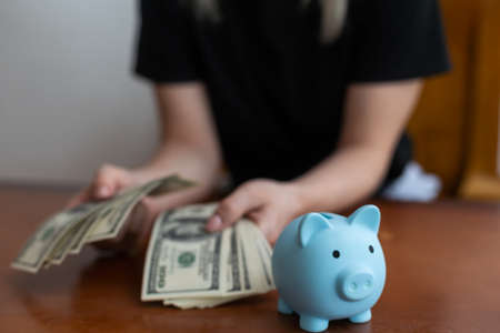 a woman keeps money in a piggy bankの写真素材