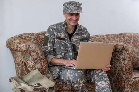 Smiling young man in navy uniform holding a laptop against white background.の写真素材