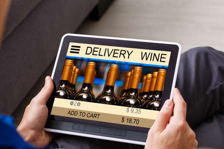 Person holding tablet and buying wine online.の写真素材