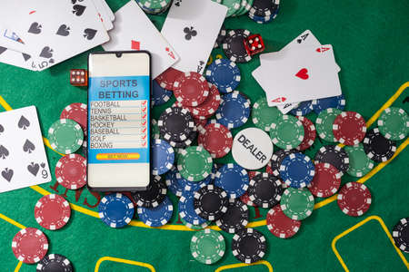 Smartphone with poket table on screen, playing cards and chip cards on poker table. Online casino.の写真素材