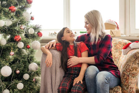 A closeup of a happy mother hugging her daughter, Christmas mood in a cozy houseの写真素材