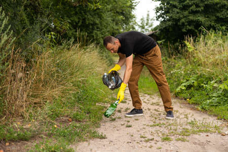 young man picking up trash outdoor. close upの写真素材