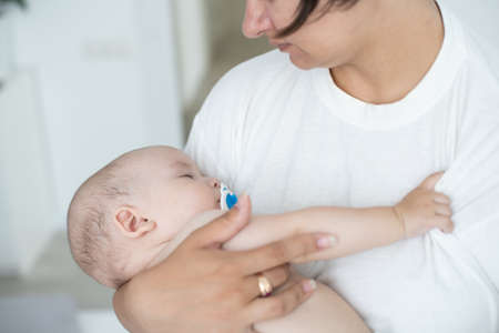 A young mother is holding her newborn baby. Mother of a nursing baby. Mother breastfeeding her baby. The family is at home. Portrait of a happy mother and childの写真素材