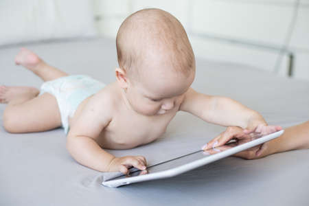 baby boy playing with digital tablet isolated on whiteの写真素材