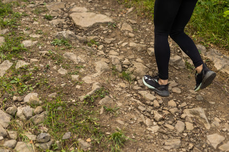young fitness woman legs walking on forest trail.