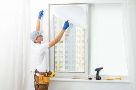 master puts a new double-glazed window in a plastic windowの写真素材
