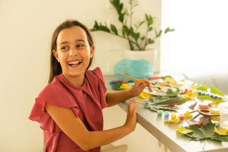 Little girl painting on autumn yellow leaves with gouache, kids arts, children creativity, autumn art.の写真素材