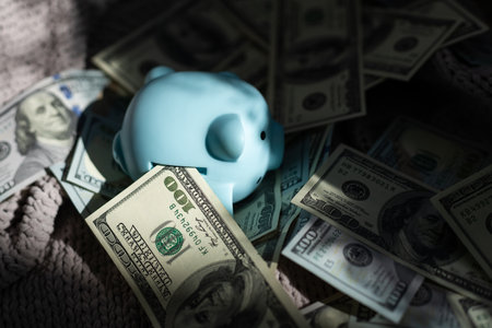 Piggy bank placed up to its nose in a pile of dollars.の写真素材