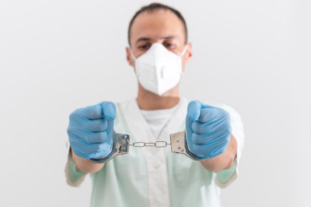 Corona virus prevention face masks at home. Hands in handcuffs medical respiratory bandage face on white backgroundの写真素材