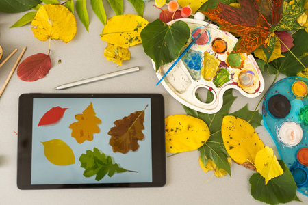 Autumn still life: apples, yellow leaves, tablet and colored pencils view from above. Autumn...
