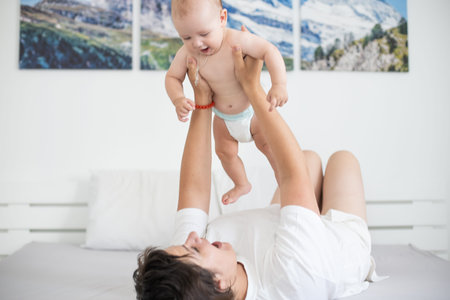 Happy smiling mother and baby lying on bed at home