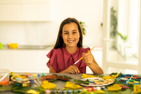 child paints leaves with paints, draws a picture, making prints of leaves. Childrens creativity in...