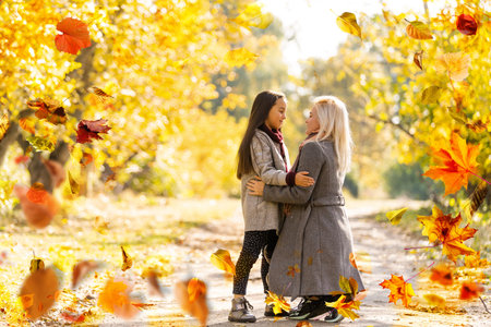 Happy family on autumn walk Mother and daughter walking in the Park and enjoying the beautiful...