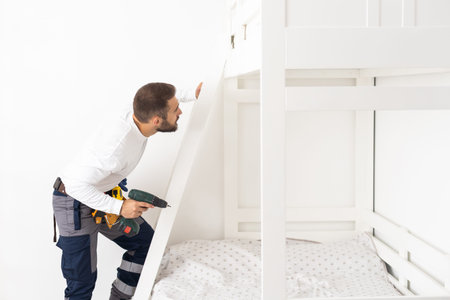 A man with instructions for assembling furniture is going to assemble in a childrens bedroom