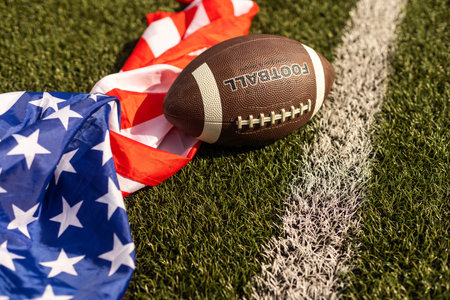 American football on green grass, on flag of United States of America background.の写真素材