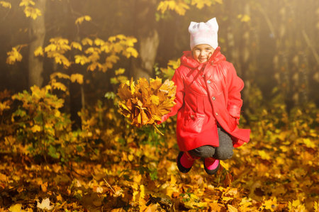 Young daughter playing in autumn parkの写真素材