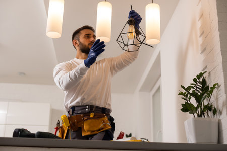 Electrician worker man assembling electric lamps in new apartment.の写真素材