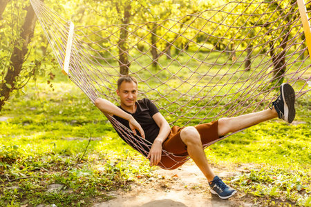 Smiling handsome man lying on hammok outdoors