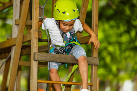 Adorable little girl enjoying her time in climbing adventure park on warm and sunny summer day. Summer activities for young kids. Child having fun on school vacations.の写真素材