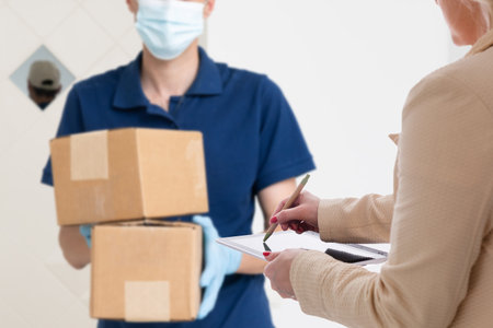 delivery, mail, people and shipping concept. Young woman sign in tablet after receiving parcel from...