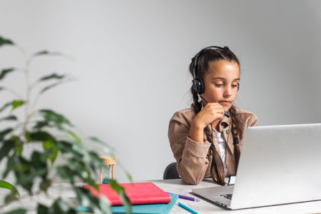 E-Learning. Shocked Little Schoolgirl Looking At Laptop Wearing Headphones Looking At Computer Web...