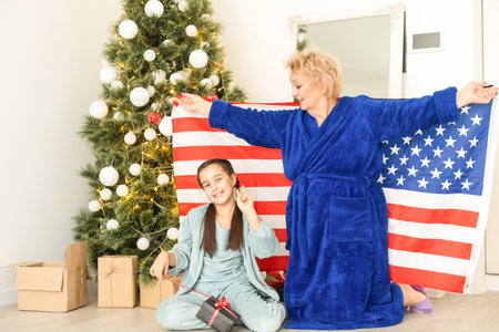 Family holding flag of USA at christmas. grandmother and granddaughterの写真素材