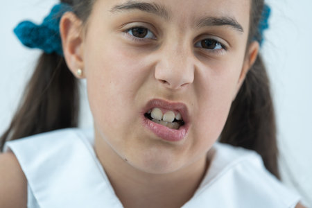 Adult permanent teeth coming in front of the child baby teeth: shark teeth. Little girls open mouth....