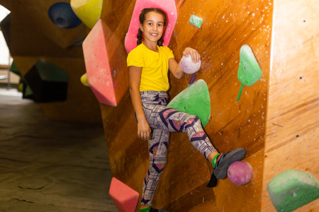 Cute little girl climbing on artificial boulders wall in gymの写真素材