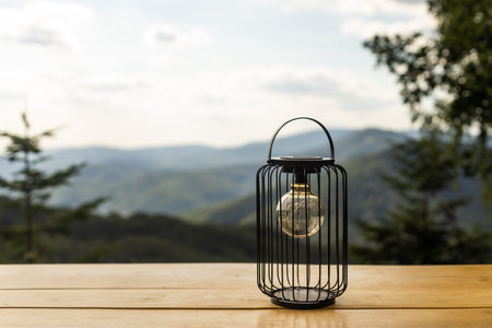 An old lamp lit with the sunset sky and mountains in the background.の写真素材