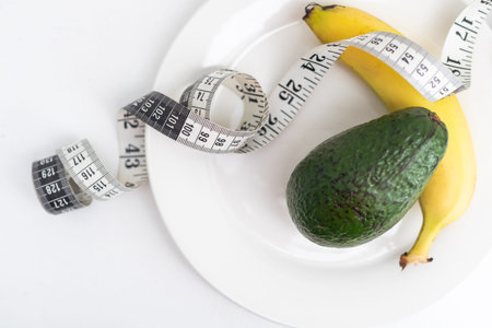 measuring tape and banana avocado in a white plate