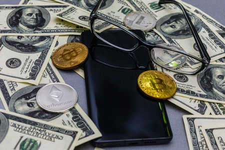 Glasses, smartphone with financial charts, wallet, crypto-coins, lying orange alarmclockの写真素材