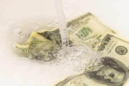 Cleaning a dirty American one hundred dollar bill. money on the black market. Banknotes of 100 dollars in the hands of men near water jets in washbasinの写真素材
