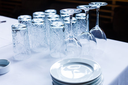 Empty glasses for wine, water, beer, drinks on white table. Glasses turned upside down. Arrangement...