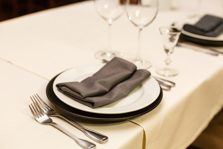Table setting for a formal ceremony, celebration, banquet. White porcelaine plate and grey napkin, wine glasses, cutleryの写真素材