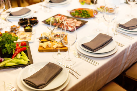 Restaurant table served with assortment of meals. Plate with vegetables, cheese platter, fish platter. Banquet, reception, celebrationの写真素材