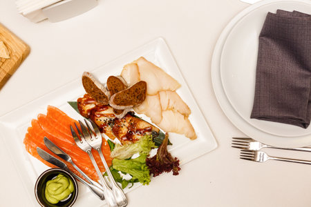 One piece of baked salmon grilled pepper lemon and salt on a brown plate with lettuce leaves. wood backgroundの写真素材
