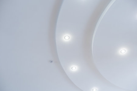 suspended ceiling with halogen spots lamps and drywall construction in empty room in apartment or house. Stretch ceiling white and complex shapeの写真素材