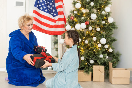 Family holding flag of USA at christmas. grandmother and granddaughterの写真素材