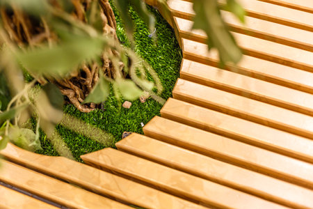 The long benches curved at corners stretch from the edge of the frame and look into the distance between the benches flowerpots with green leafy bushes in stone flowerpotsの写真素材