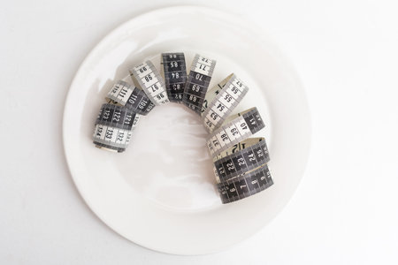 Medical starvation for lose weight. Empty plate and measuring tape on white background top view...