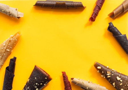 fruit rolls of orange, mango, banana on a yellow background close-upの写真素材