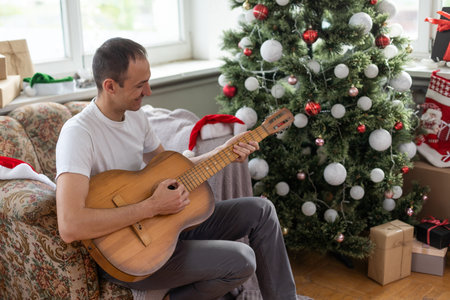 Portrait of young man celebrating party of his birthday at home and playing guitar.