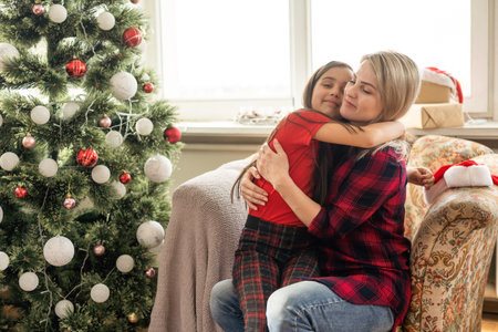 A closeup of a happy mother hugging her daughter, Christmas mood in a cozy houseの写真素材
