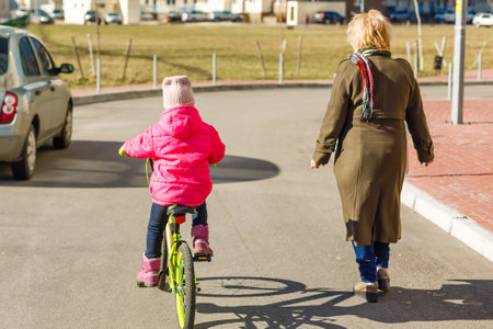 little girl riding bicycle in city park.の写真素材